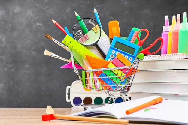 Papelería para la escuela en un carro en el fondo de una pizarra