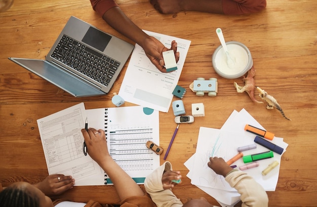 Papeles de escritura y de impuestos de padres con niños de escuela en casa ocupados con trabajo remoto en una casa familiar Vista superior de un niño en una mesa mientras mamá y padre trabajan en auditoría financiera y documentos comerciales