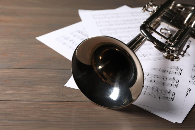 Papeles de trompeta y partitura con notas en un primer plano de mesa de madera Espacio para texto