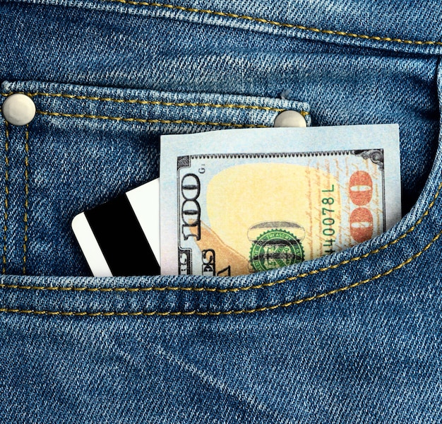 Papier amerikanische Dollar und Plastikbankkarte mit Magnetstreifen in der Tasche der Blue Jeans, Nahaufnahme