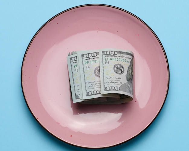 Papier-amerikanische Dollarscheine in einer keramischen rosa Platte auf einem blauen Ba
