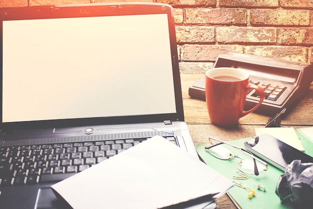 Papier auf Notebook, Tasse Kaffee und Taschenrechner auf Holz