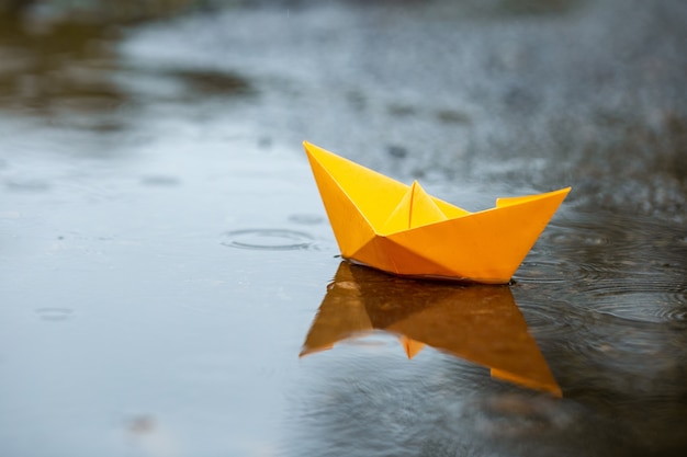 Foto papier handgemachtes gelbes bootsspielzeug auf einer pfütze in einem regen