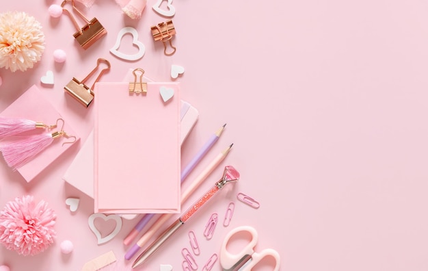 Papier mit einem Clip Rosa Schulzubehör und Herzen auf hellrosa Draufsicht Mockup Girly Arbeitsplatz mit Notizbuch Schere Bleistift Stift Büroklammern Karten und Uhr Zurück zur Schule