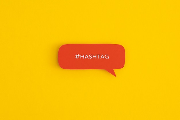 Papier-Sprechblase mit dem Wort Hashtag auf gelbem Hintergrund Draufsicht mit Kopienraum Flat Lay