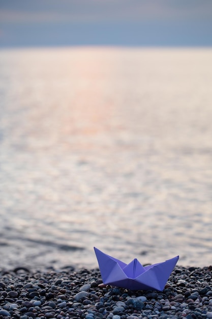 Papierboot am Meer bei Sonnenuntergang