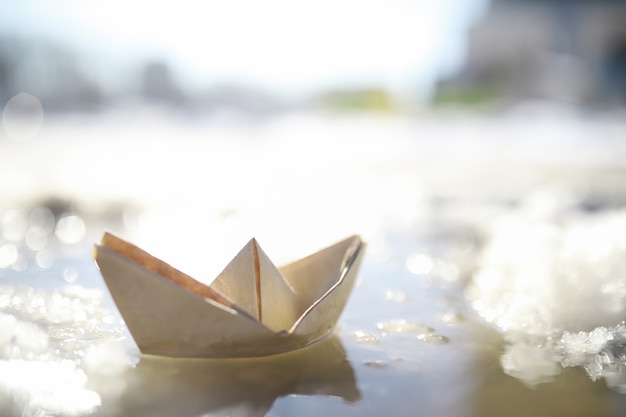 Foto papierboot im wasser auf der straße. das konzept des frühen frühlings. schmelzender schnee und ein origami-boot auf wasserwellen.