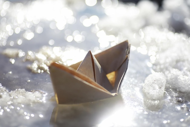 Papierboot im Wasser auf der Straße Das Konzept des frühen Frühlings Schmelzender Schnee und ein Origami-Boot auf Wasserwellen