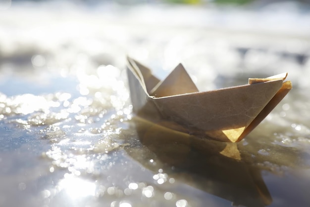 Papierboot im Wasser auf der Straße Das Konzept des frühen Frühlings Schmelzender Schnee und ein Origami-Boot auf Wasserwellen