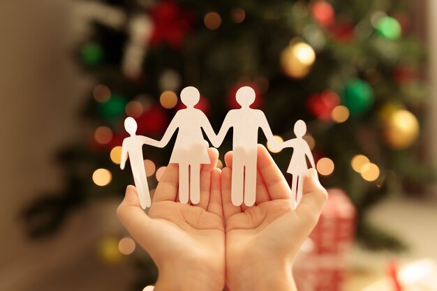 Papierfamilie auf dem Hintergrund eines Weihnachtsbaumes