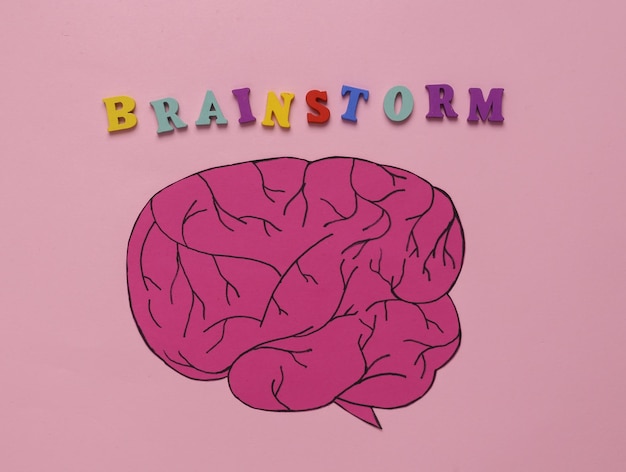 Papiergeschnittenes Gehirn mit der Inschrift "Brainstorm" auf rosa Hintergrund