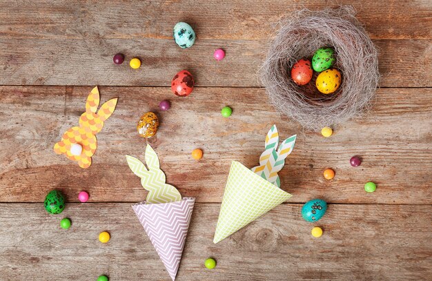 Papierhäscheneier und -bonbons auf hölzernem Hintergrund Ostern-Zusammensetzung