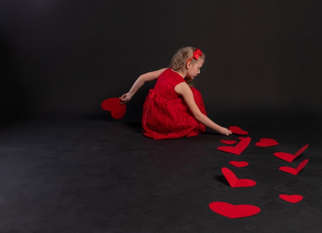 Papierherzen valentinstag auf den bodenherzen schöne 14. februar flitterwochen emotion gefühl rahmen im roten kleid mädchen barfuß