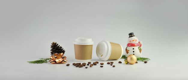 Papierkaffeetasse und Kaffeebohnen auf weißem Hintergrund.