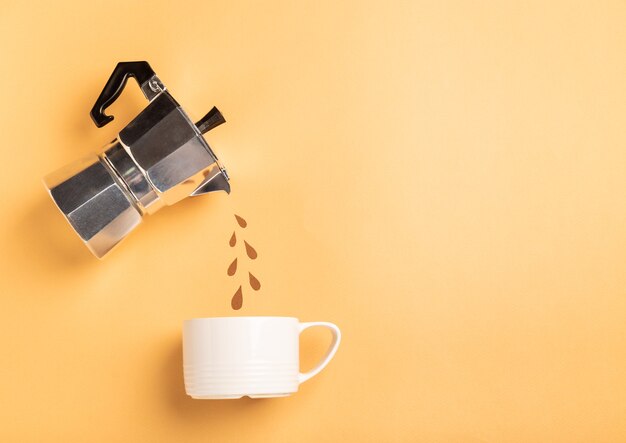 Papierschnitttropfen, die von einer Geysir-Kaffeemaschine in eine Tasse auf gelbem Papierhintergrund gießen. Kaffeezubereitungskonzept. Draufsicht, flach liegen. Minimalistisches Design. Platz für Text.