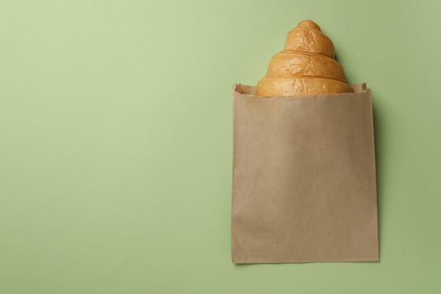 Papiertüte mit Croissant auf Grün