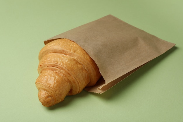 Papiertüte mit Croissant auf Grün