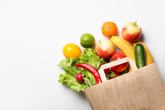 Papiertüte mit Gemüse und Früchten auf einem weißen Hintergrund. Online-Bestellung in einem Lebensmittelgeschäft. Das Konzept der richtigen Ernährung. Lebensmittellieferservice.