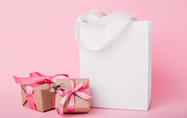 Papiertüte und Geschenkboxen isoliert auf rosa