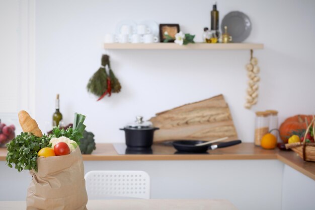 Papiertüte voller Gemüse auf dem Tisch in der Küche Gesundes Essen und vegetarisches Konzept