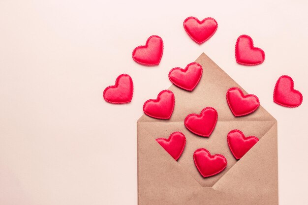 Papierumschlag mit roten Satinherzen. Valentinstag Cocept