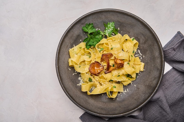 Pappardelle de pasta italiana tradicional con champiñones rebozuelos queso y perejil en placa oscura