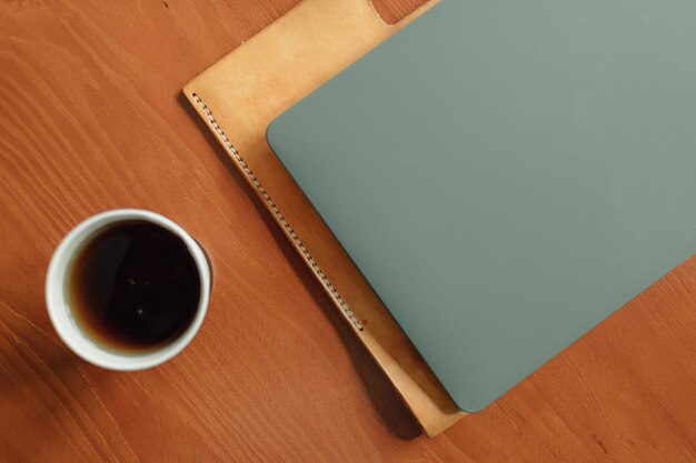 Pappbecher heißes Getränk und Laptop auf dem Tisch. Konzept der Arbeit von zu Hause aus.