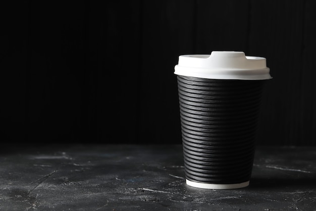 Pappbecher Kaffee auf dem Tisch auf dunklem Hintergrund. Mockup-Design. Platz für Text. Ein Platz für das Logo.