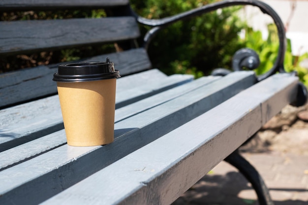 Pappbecher mit Kaffee auf Parkbank-Kopienplatz