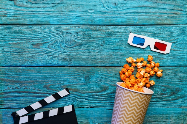 Pappbecher mit Popcorn über blauem alten Holztisch