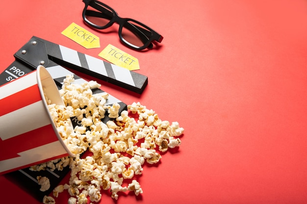 Foto pappbecher mit popcorn und filmklappe auf rotem grund. platz für text