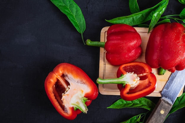 El paprika cortó por la mitad en una tabla de cortar de madera en un fondo negro.