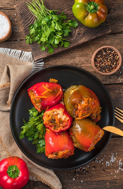 Paprika gefüllt mit putenreis und gemüse auf braunem hintergrund mit frischen kräutern