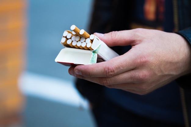 Paquete abierto de cigarrillos en la mano de un hombre