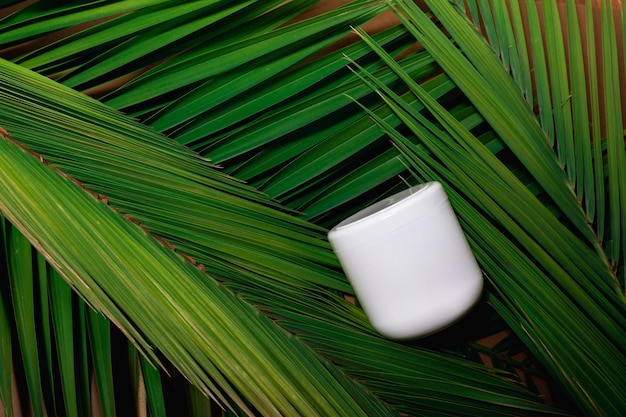 Paquete de botella blanca de loción cosmética para el cuidado de la piel de belleza sobre fondo de hojas de palmeras tropicales