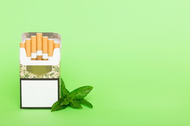 Paquete de cigarrillos mentolados y menta fresca en la mesa de colores Cigarrillos mentolados vista superior plana