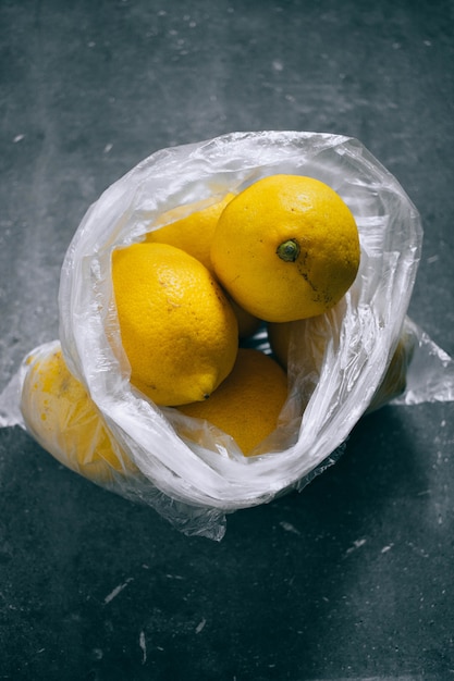 Un paquete de cítricos, limones sobre un fondo gris.