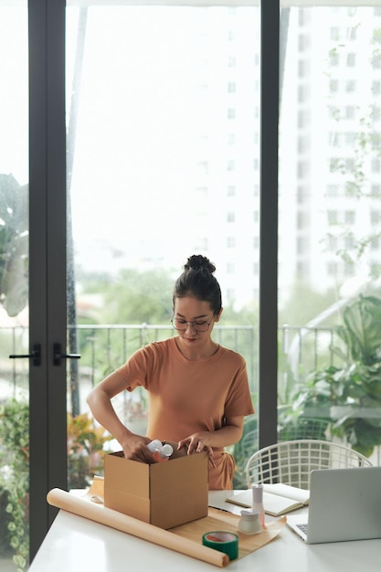 Paquete de embalaje de mujer joven en la habitación