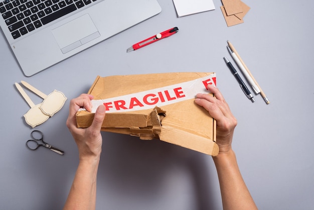 Paquete frágil roto, caja de cartón rota en el escritorio de oficina