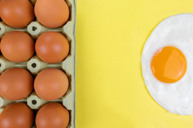 Paquete de huevos marrones crudos y un huevo frito soleado con espacio de copia en el medio