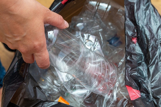 Paquete negro con muchas botellas de plástico usadas para reciclar en las manos