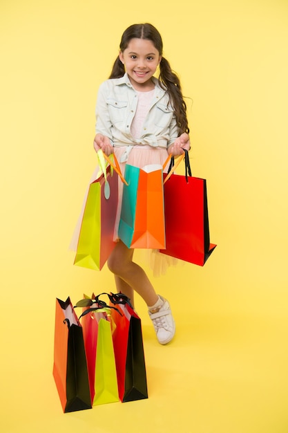 Paquete y niña niña con paquete colorido paquete de compras en mano de niña niña con bolsa de paquete pequeña adicta a las compras