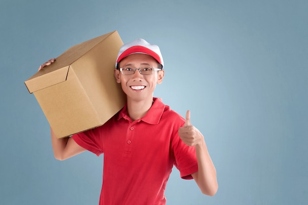 Paquete que lleva asiático joven del hombre de entrega y que muestra el pulgar para arriba