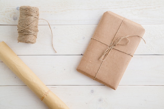 Paquete, regalo Embalado en papel ecológico y cordel para embalar sobre fondo de madera clara. la vista desde arriba