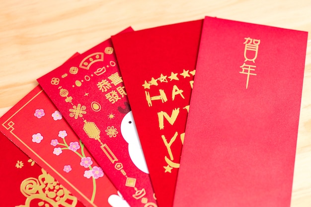 Paquete de sobres rojos año nuevo chino, hongbao con el carácter 'Feliz año nuevo' sobre fondo de madera para el año nuevo chino. Traducción: buena suerte en el año