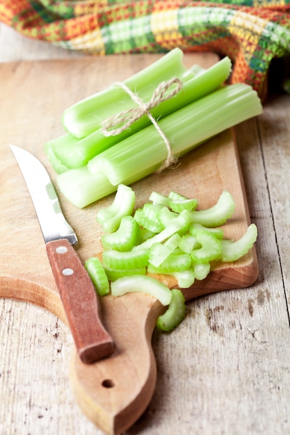 Paquete de tallos de apio verde fresco y cuchillo
