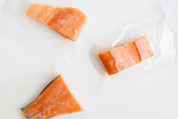 Paquete de tres filetes de pescado de salmón congelado en pequeñas bolsas de plástico Envase al vacío Filetes de pescado rojo crudo