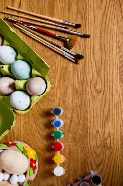 Paquete de vista superior de huevos con pintura de pincel y elementos decorativos sobre fondo de madera Espacio de copia Feliz Pascua DIY endecha plana