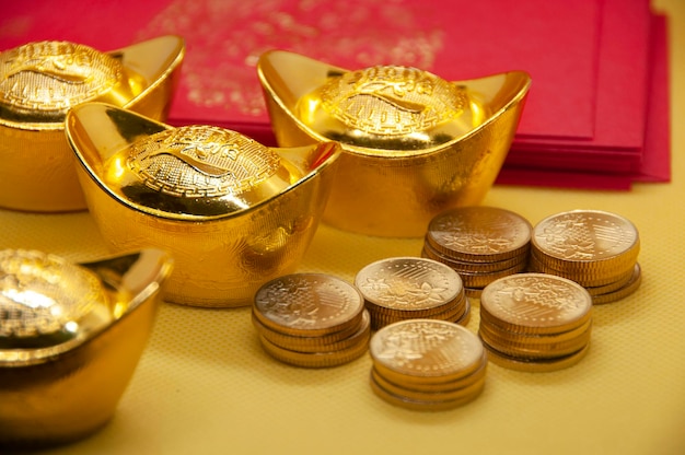Foto paquetes de año nuevo chino con lingotes de oro chinos y monedas de oro sobre fondo amarillo concepto de temporada festiva
