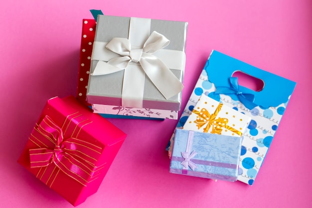 Paquetes sorpresa de regalo coloridos, sobre fondo rosa.